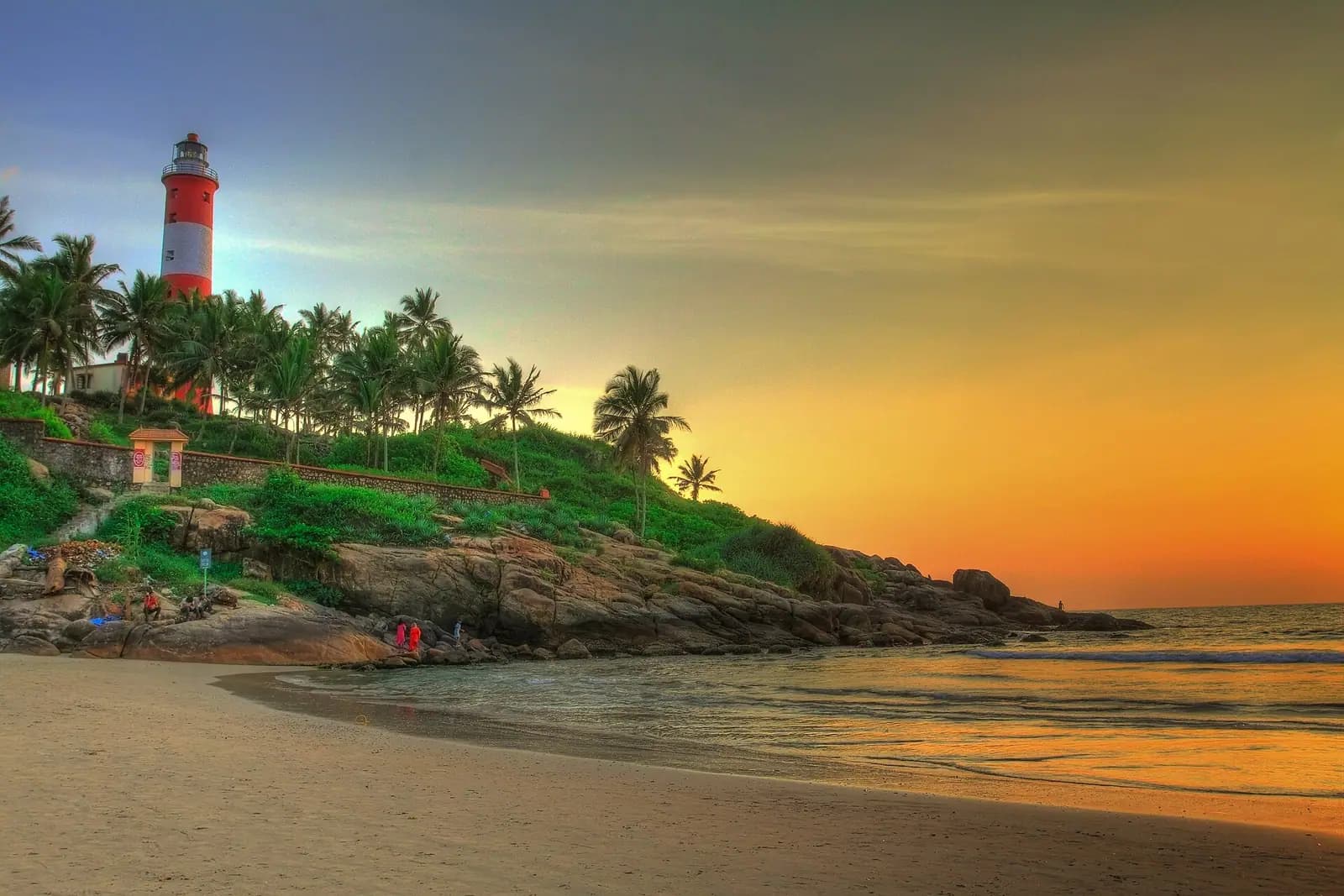 The striped lighthouse above the crescent of Kovalam beach in Kerala