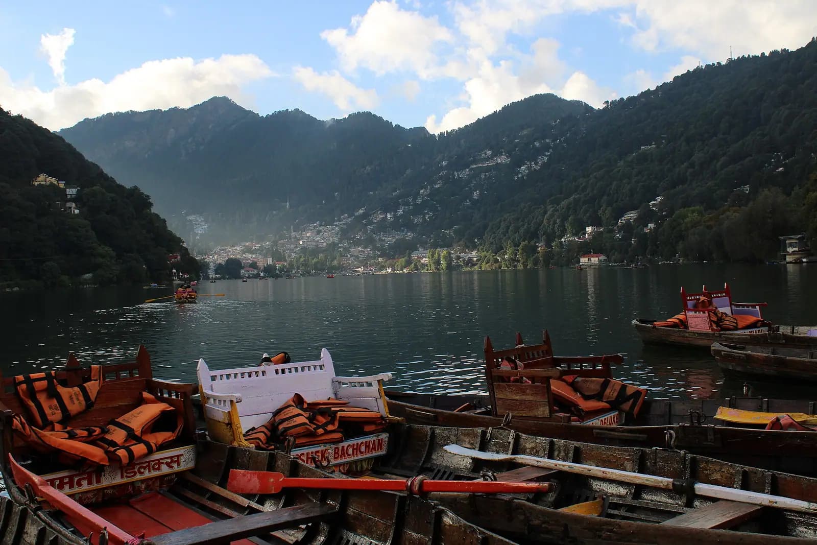 Boats on Naini lake with the town rising on the slopes around it, Nainital, Uttarakhand